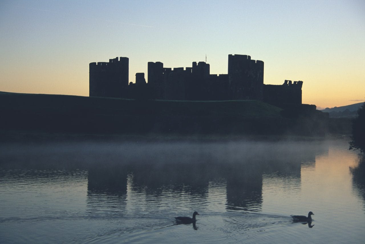 Caerphilly Castle at sunset with a light mist on the moat