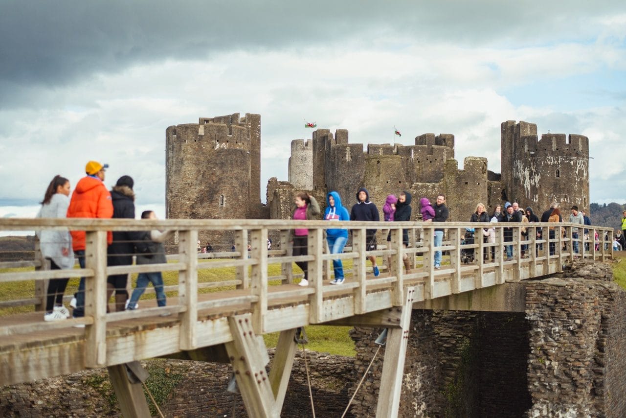 Tourist crossing the moat bridge at Caerphilly Castle