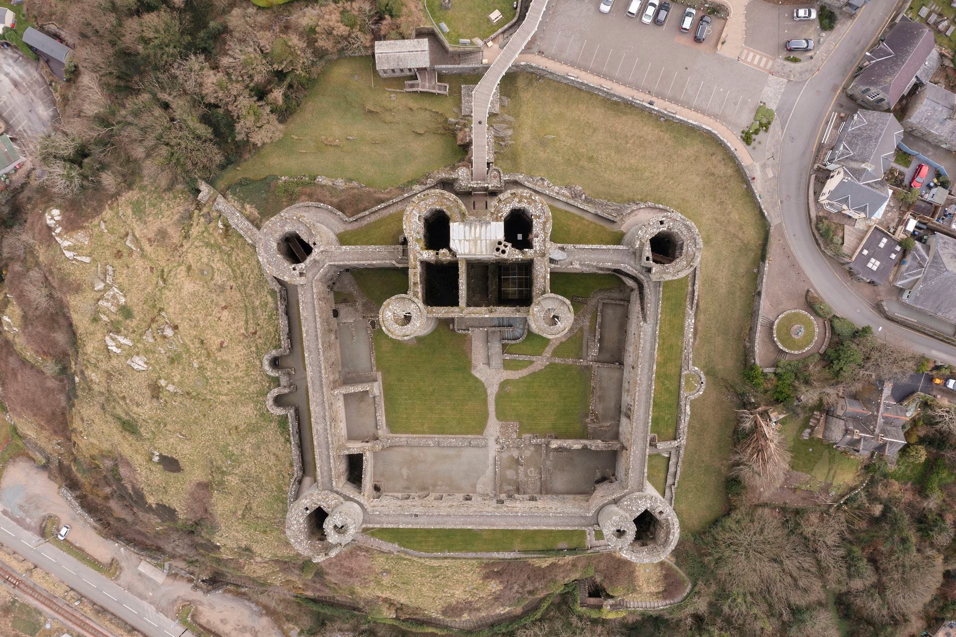 Overhead view of the grassy inner ward of Harlech Castle, enclosed by the castle's concentric stone walls and twin-towered gatehouse