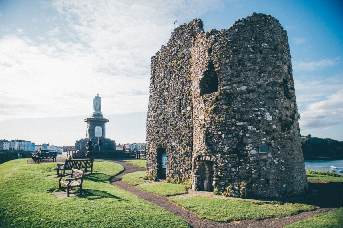 The historic stone ruins of Tenby Castle on Castle Hill, a popular grassy viewpoint with benches looking out toward Caldey Island.