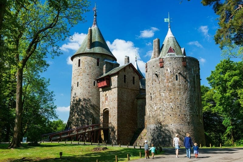 Castell Coch  with a family walking towards the castle and bright blue sky in the background