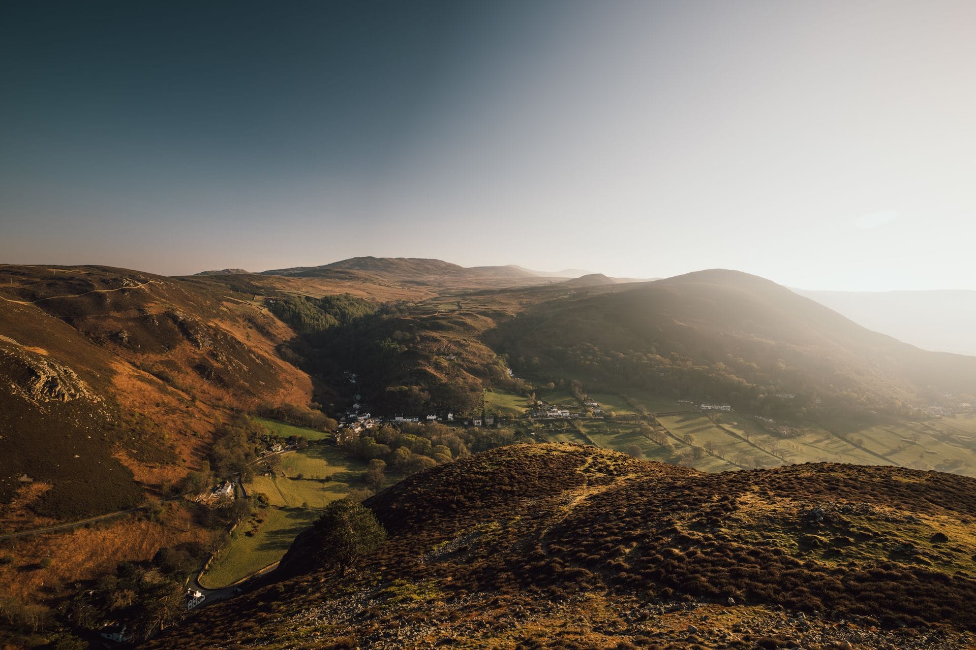 The grassy summit ridge of Conwy Mountain in north Wales, with panoramic views across the Conwy Estuary to Eryri (Snowdonia) under a bright sky