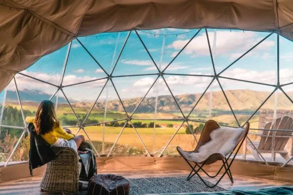 Woman looking out at nature from geo dome tent, one of the many glamping in Wales options to try