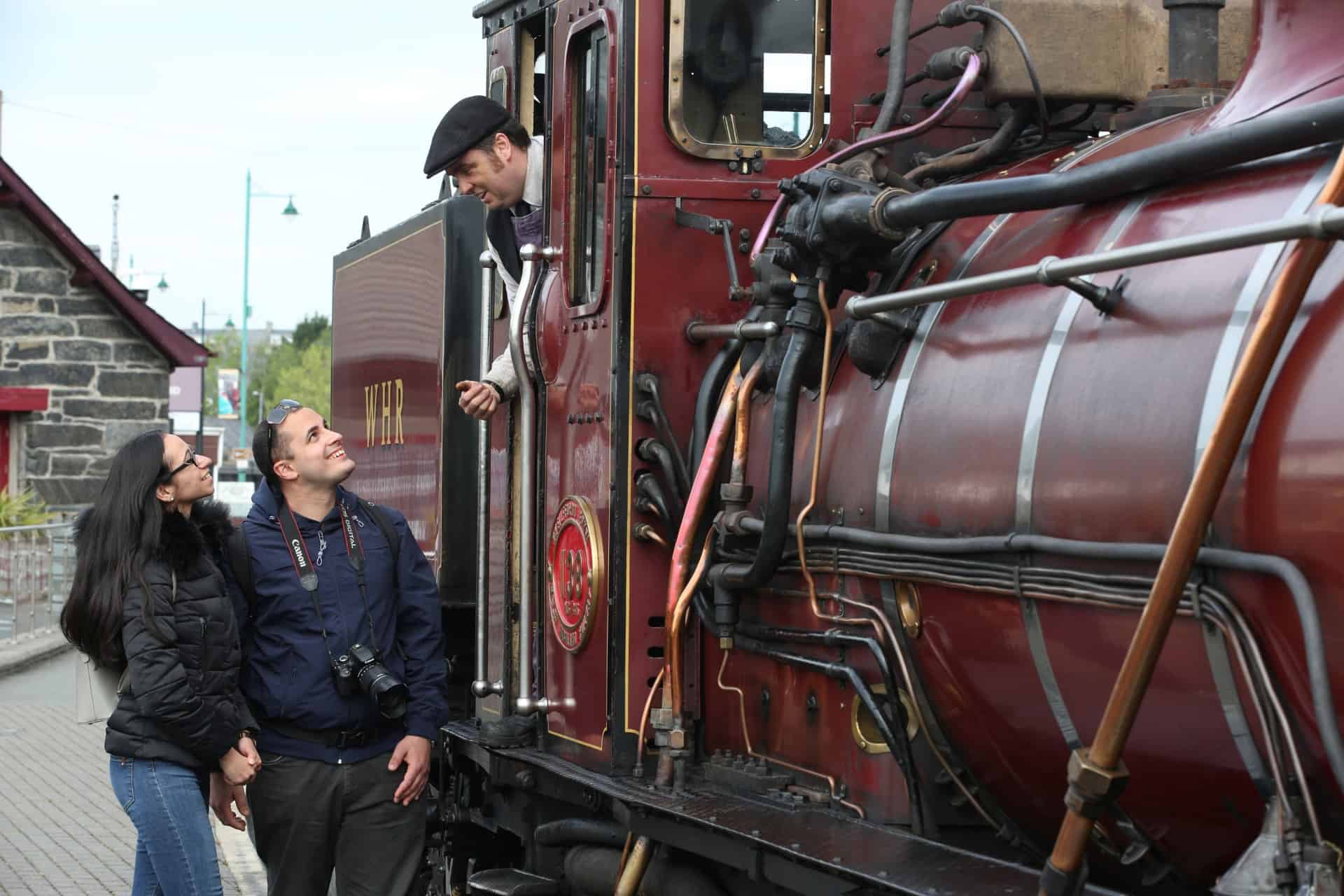 A couple talking to a steam railway driver in Wales
