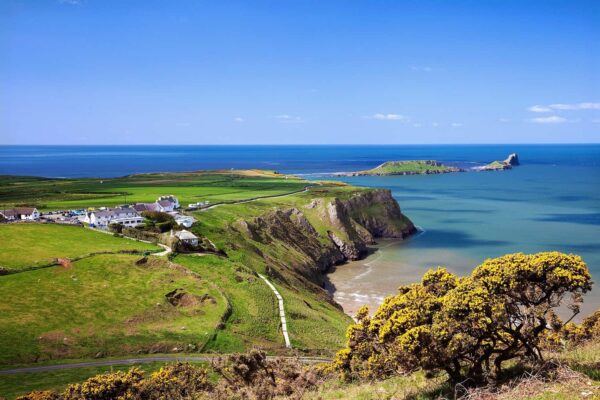 High-angle view of Rhossili Bay with the tidal island of Worm's Head stretching into the bright blue Atlantic Ocean