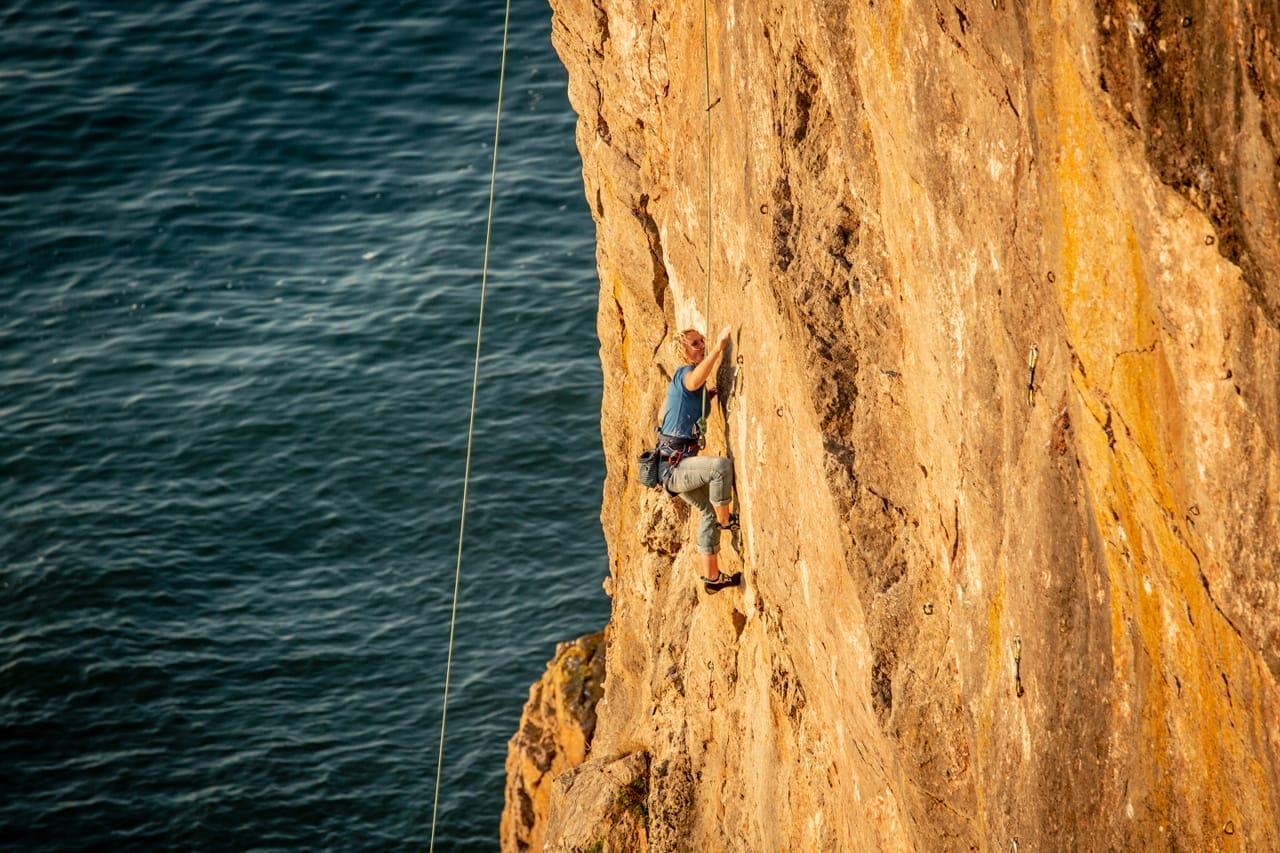 Person enjoying a rock climbing adventure in Wales along the coast of Carmarthenshire