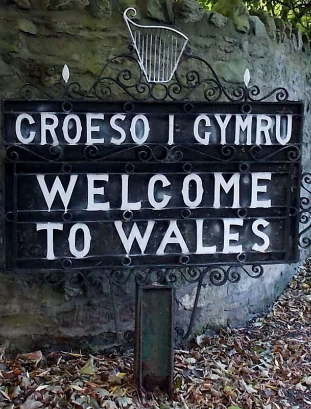 A black wrought-iron sign with white text reading