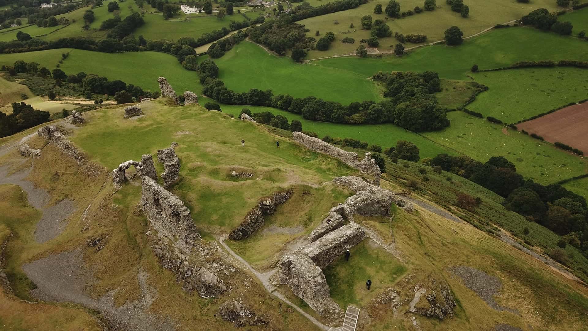 Wide panoramic view of the medieval castle ruins of Castell Dinas Brân standing on a prominent green hill overlooking the Dee Valley in Llangollen, North Wales.