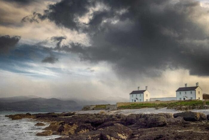 Stormy sky with a holiday cottage in Snowdonia in the background at Penmon Point, Anglesey