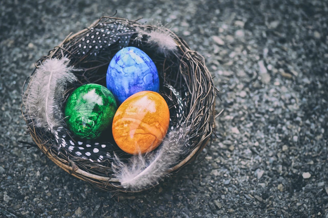 A blue, green and orange Easter egg in a wicker basket