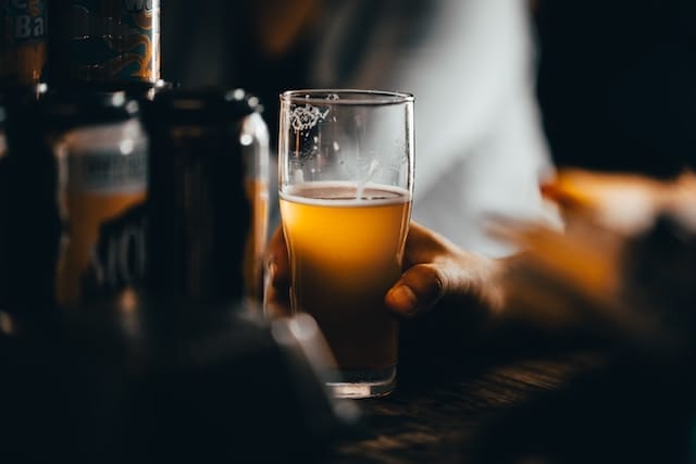 pint of craft beer being held by a man sitting at a table