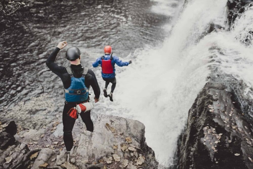 Coasteering group jumping into the sea from cliffs in Pembrokeshire, Wales