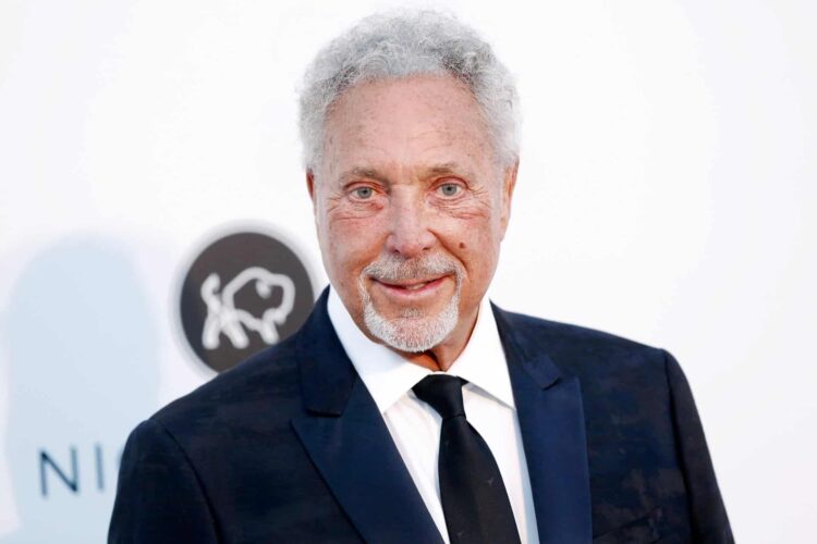 Welsh singer Sir Tom Jones smiling in a dark suit and tie - discover more fun facts about Wales.