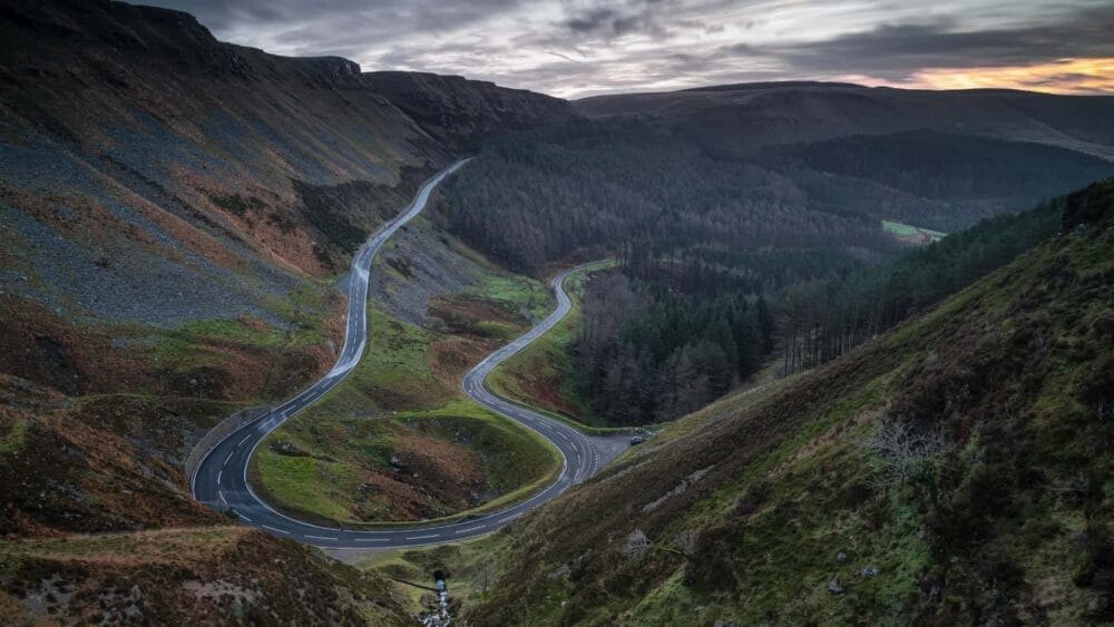 Scenic road winding through Eryri (Snowdonia) National Park with mountains either side, North Wales