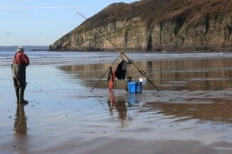 Fishing tackle set up on a beach with a cliff in the background