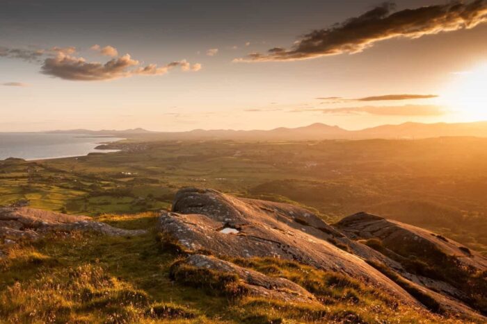 Sunset over Criccieth Bay and the Lleyn Peninsula as seen from the summit of Moel-y-Gest mountain near Porthmadog in the Snowdonia National Park of North Wales.