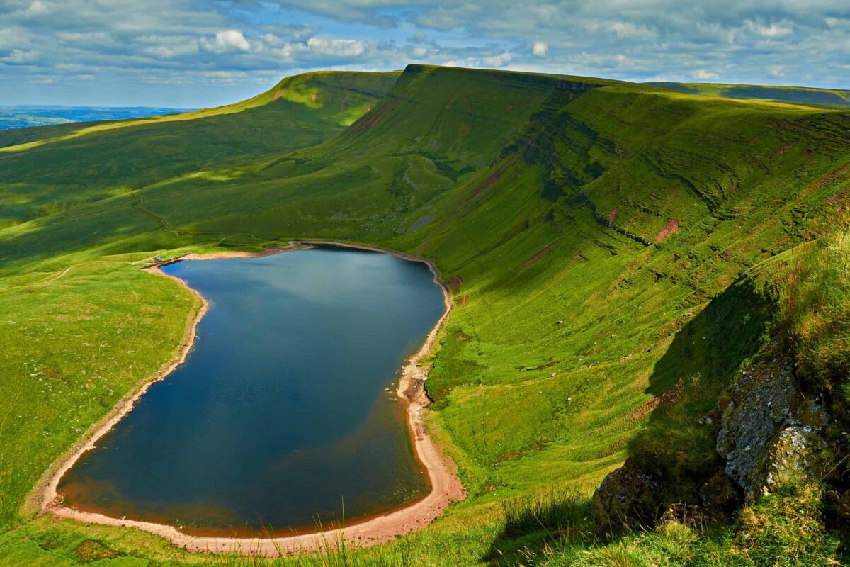 Llyn-y-Fach lake from the Beacons Way in The Black Mountain area of the Brecon Beacons National Park. The footpath continues along the top of the scarp to the peaks of Fan Foel and Fan Brycheiniog.